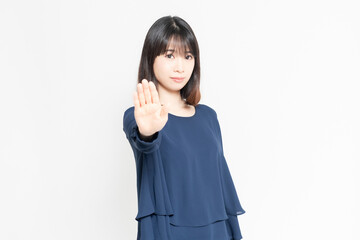 白い背景の前に立ってNGのポーズをする若い女性