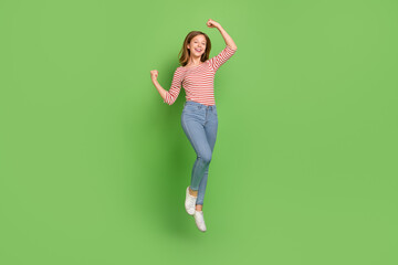 Photo of champion lady jump raise fists rejoice goal achievement wear striped shirt jeans isolated...