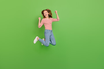 Photo of astonished glad lady jump celebrate triumph wear striped shirt isolated green color...