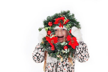 Smiling Funny Face of emotional Girl in Christmas wreath, isolated on white background. Happy child in winter clothes