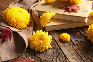 Yellow chrysanthemum flowers and books on wooden background