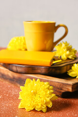 Yellow chrysanthemum flowers, cup of tea and book on color grunge background
