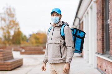 food shipping, pandemic and people concept - delivery man in protective medical mask with thermal...
