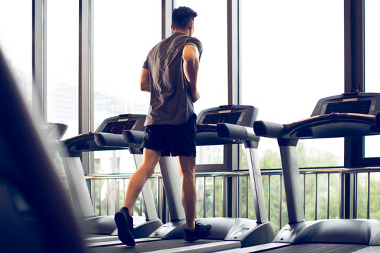 Young man running on treadmill at gym