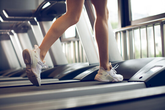 Young woman running on treadmill at gym
