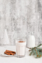 Glass of tasty coffe with cinnamon on light background