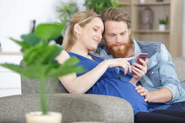 Fototapeta premium beautiful young pregnant couple using the phone