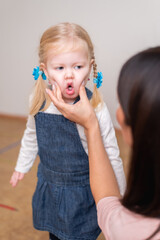 Woman speech therapist teaches a girl the correct pronunciation and literate speech