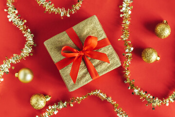 Golden gift box with christmas ornaments on a red background. Holiday concept.