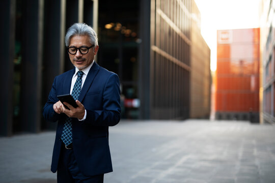 Senior businessman outdoors. Middle-aged businessman using the phone... - Powered by Adobe