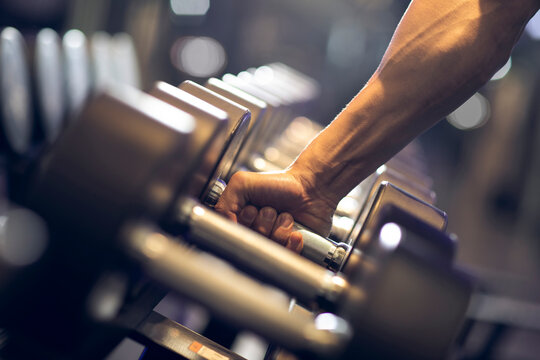 Young man working out with dumbbell at gym