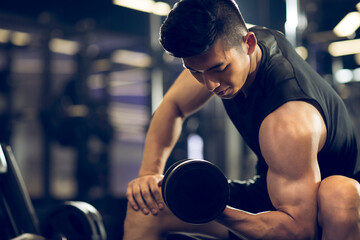 Young man working out with dumbbell at gym