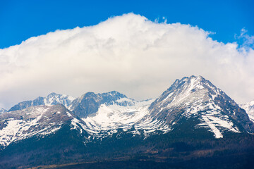 slovakia countryside landscape in spring. gorgeous High Tatra mountain ridge with snow capped peaks in the distance. grassy rural fields on a sunny day with clouds on a blue sky