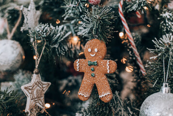 Close-up photo of a gingerbread man ornament hanging on a christmas tree