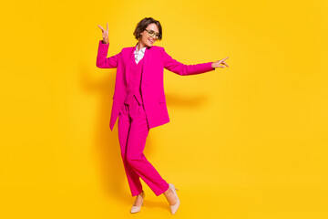 Photo of pretty adorable young woman dressed pink suit glasses smiling dancing pointing fingers isolated yellow color background