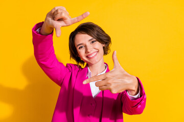 Photo of adorable pretty young woman dressed pink suit smiling showing photo gesture isolated yellow color background