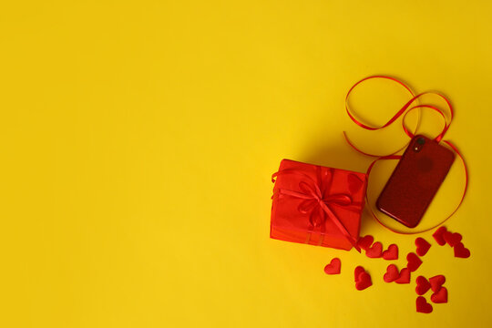 A red gift and hearts on a yellow background. Picture for Valentine's Day. The concept of gifts and lovers. High-quality photography
