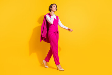 Photo of dreamy sweet young woman dressed pink suit smiling walking empty space isolated yellow color background