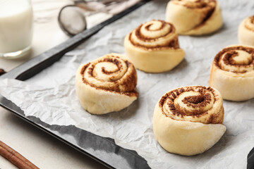 Baking dish with uncooked cinnamon rolls on light background, closeup