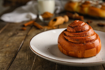 Plate of tasty cinnamon roll on wooden background
