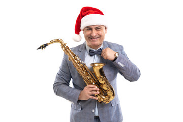 Funny musician wears in Santa's hat holds saxophone while straightening bow tie on studio background