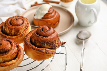 Grid with tasty cinnamon rolls on white wooden background, closeup