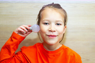 A girl demonstrates a light bulb as a symbol of light and new technologies in the modern world