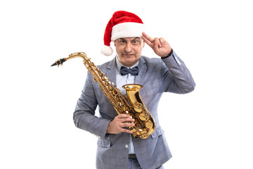 Sceptical man wears in Santa's hat holds saxophone while raising hand to head on studio background
