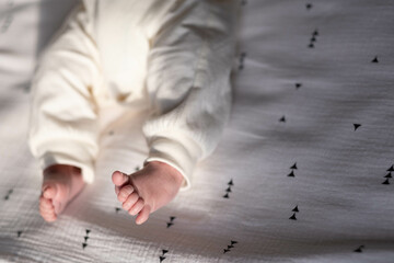 Charming legs of a newborn baby lying on a light bed