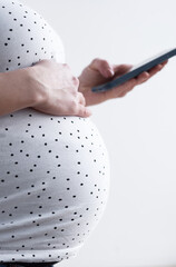 A pregnant woman stands in the background of a window using a phone