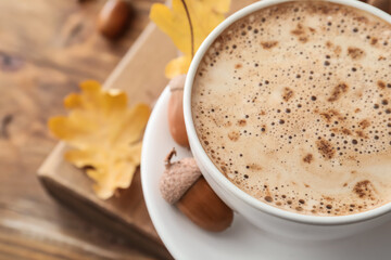 Cup of coffee with acorns on table, closeup
