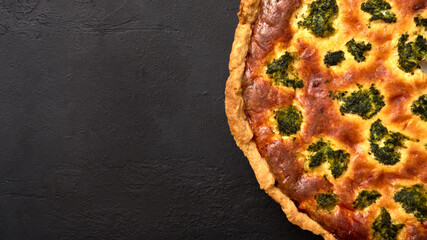 Homemade quiche pie with broccoli, tuna and cheese on black graphite background. Panoramic view, copy space