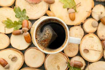 Cup of coffee with acorns and autumn leaves on table