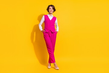 Full length body size view of attractive cheerful businesswoman holding hands in pockets isolated over bright yellow color background