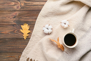 Cotton flowers, warm scarf and cup of coffee on wooden background