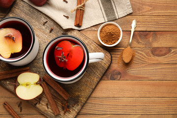 Cups of tasty apple tea with cinnamon on wooden background