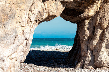 natural arch on the seashore, behind which sea surf can be seen