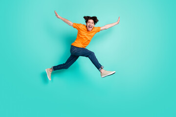 Fototapeta na wymiar Full size photo of cool brown hair young guy jump yell wear t-shirt jeans sneakers isolated on blue background