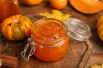 Jar of sweet pumpkin jam on wooden background
