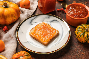 Plate with toast with sweet pumpkin jam on grunge background