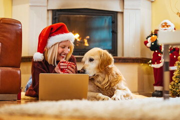 Smiling women sitting on couch in living room with her dog, christmas tree in background. They just...