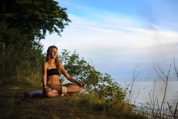 Fototapeta na wymiar junge Frau sitzt in der Natur und meditiert im Schneidersitz