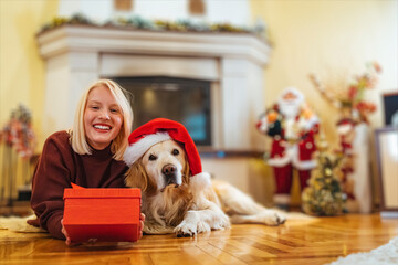 Photo of young woman and her pet enjoying together at home. Christmas time with my favorite person. Family celebrating christmas. Young woman celebrating New Year at home with her dog...
