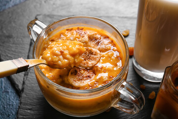 Pot of tasty oatmeal with pumpkin on black background