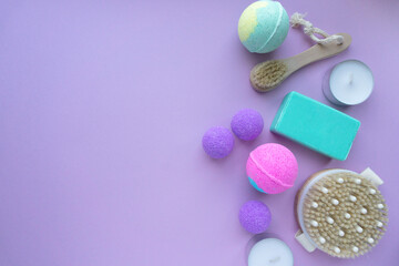 Spa flat lay. Bath bombs, soap and massage brushes on purple background, space for text