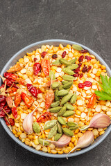 Cardamom, garlic, onion and dry pepper pods on peas in bowl.
