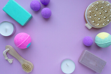 Set of spa products. Bath bombs, soap and massage brushes on purple background, space for text