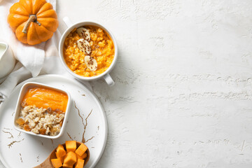 Pot and bowl of tasty oatmeal with pumpkin on white background