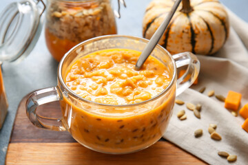 Pot of tasty oatmeal with pumpkin on blue background