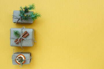 Zero waste Christmas concept. Natural gift materials paper fir branches dried citrus cinnamon on a yellow background. Flat layout top view. Eco-greeting card in pastel colors. Gifts New Year 2022